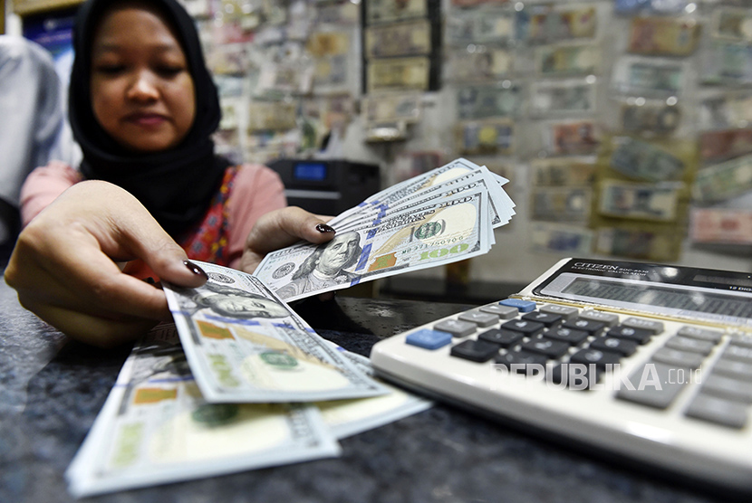 Petugas jasa penukaran uang asing menghitung pecahan 100 dolar AS di ITC Kuningan, Jakarta, Rabu (28/2).