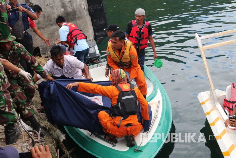 Petugas gabungan mengangkat kantong berisi jenazah korban KM Sinar Bangun yang tenggelam di Danau Toba, di Pelabuhan Tigaras, Simalungun, Sumatera Utara, Rabu (20/6).