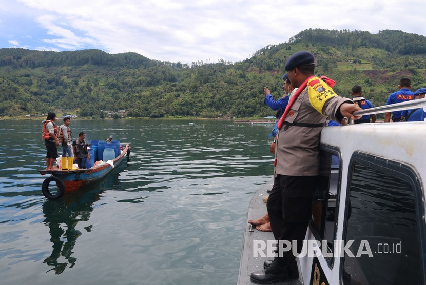 Personel kepolisian berbincang dengan nelayan saat melakukan proses pencarian korban KM Sinar Bangun yang tenggelam di Danau Toba, Simalungun, Sumatera Utara, Rabu (20/6). 