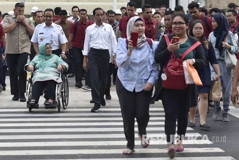 Presiden Joko Widodo (tengah) bersama Gubernur DKI Jakarta Anies Baswedan (ketiga kiri) dan ibu dari Gubernur DKI Jakarta Aliyah Rasyid Baswedan (kedua kiri) menyeberangi Pedestrian Light Control (Pelican Crossing) di Jalan MH Thamrin, Jakarta, Kamis (2/8).