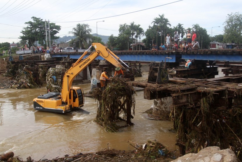 Alat berat membersihkan material banjir berupa kayu dan sampah yang tersangkut di jembatan rel kereta api pasca banjir, di kelurahan Alai Parak Kopi, Padang, Sumatera Barat, Sabtu (3/11/2018). 