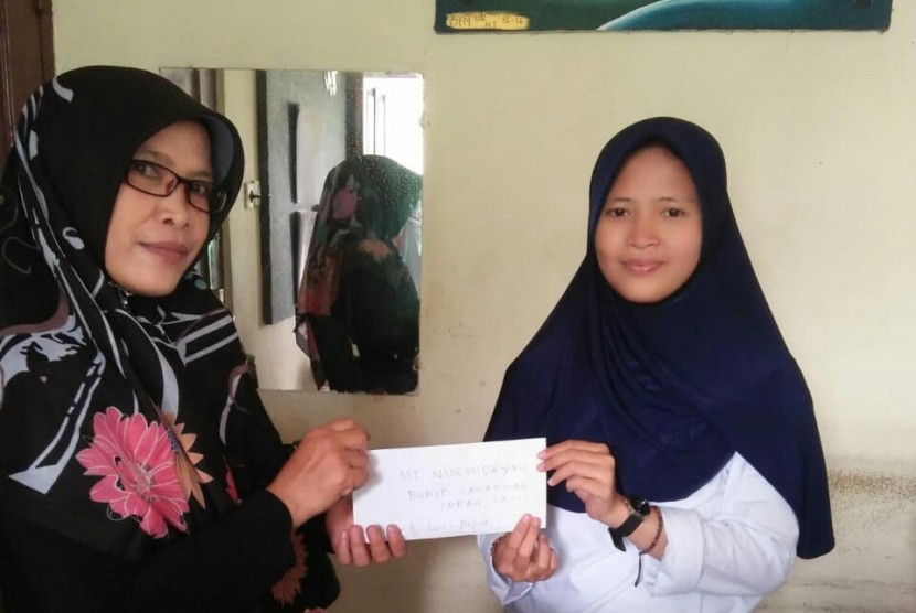 Ketua Majelis Taklim Nurhidayah BSI, Nurlinawati Sigit  menyerahkan donasi berupa uang dan mushaf Alquran kepada perwakilan Asrama Mahasiswa IIQ Jakarta yang mengalami musibah kebakaran.