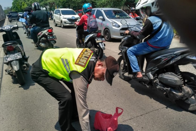 Anggota Polsek Tanjung Duren bersama warga membersihkan ranjau paku di jalan sebelah tol Tomang-Tangerang. Jumat (16/11).