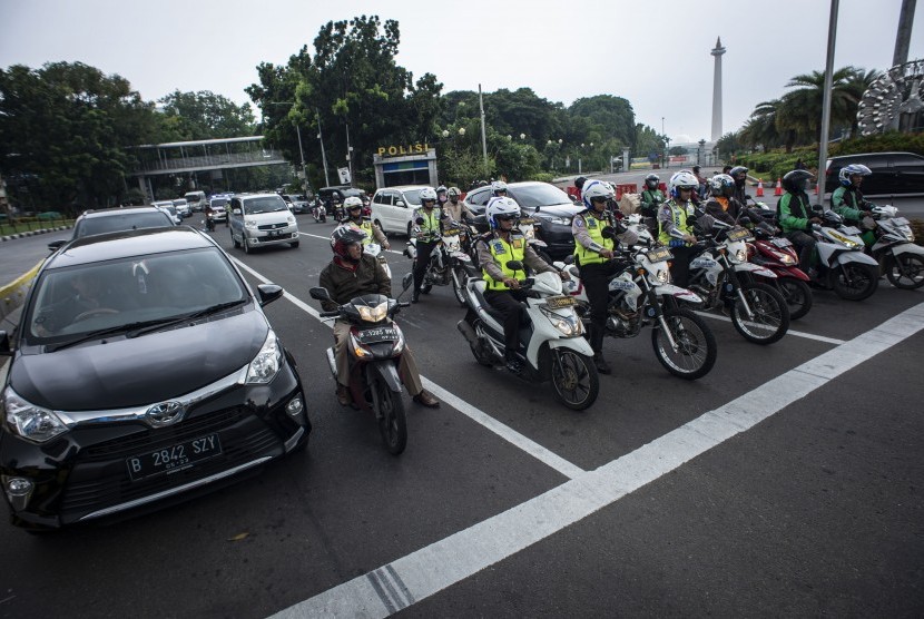 Sejumlah anggota Satlantas Polres Metro Jakarta Pusat saat melakukan sosialisasi tilang elektronik kepada masyarakat pengguna kendaraan bermotor di persimpangan Bundaran Patung Kuda, Jakarta, Senin (26/11/2018).