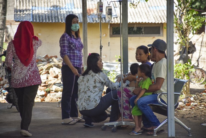 Sejumlah petugas merawat pasien di luar ruangan pasca terjadi gempa bumi di Puskesmas Malaka, Desa Malaka, Kecamatan Pemenang, Lombok Utara, NTB, Kamis (6/12/2018). 