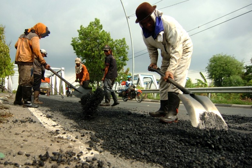 Pekerja mengerjakan pengaspalan jalan rusak di jalur Pantura Tegal, Jawa Tengah, Sabtu (8/12/2018).