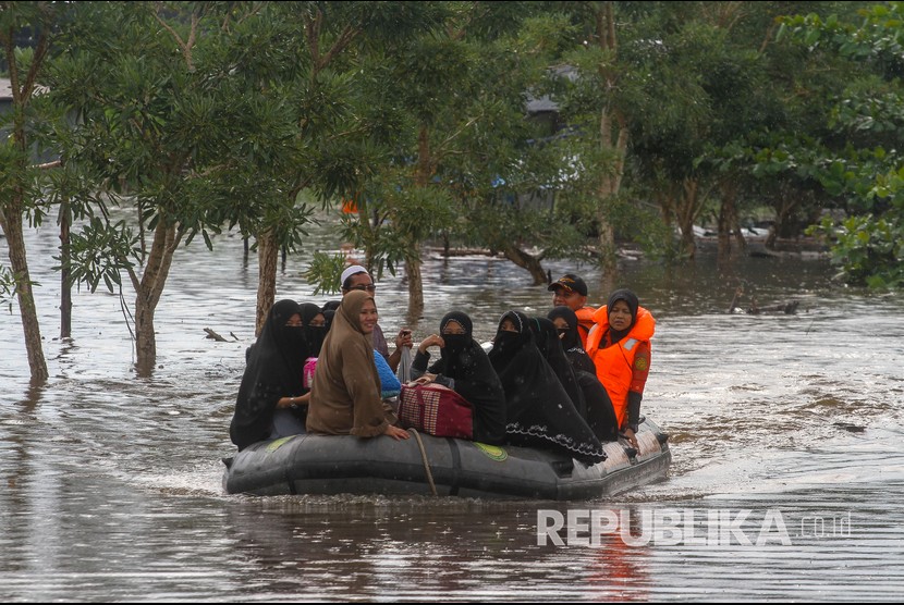 Petugas Basarnas menggunakan perahu karet mengevakuasi santri dan santriwati yang terjebak banjir di Pondok Pesantren Darul Ulum, Kecamatan Siak Hulu, Kabupaten Kampar, Riau, Rabu (12/12/2018).