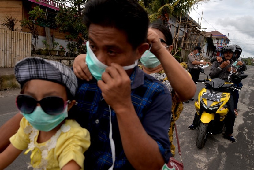 Anggota Polisi membagikan masker ke pengendara di Desa Liwutung, Minahasa Tenggara, Sulawesi Utara, Minggu (16/12/2018).