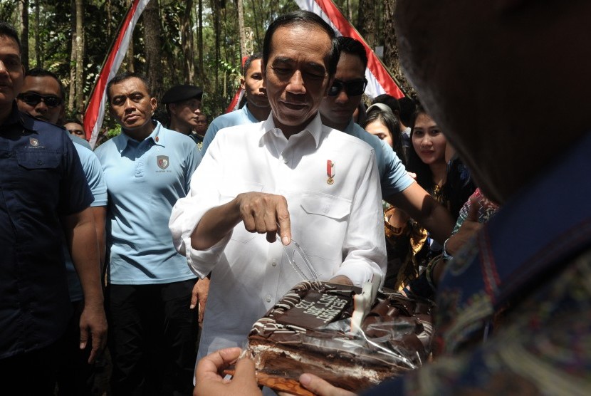 Presiden Joko Widodo (tengah) menerima kejutan kue dari warga usai Penyerahan Surat Keputusan (SK) Perhutanan Sosial di Taman Hutan Pinus Kenali, Kota Jambi, Minggu (16/12/2018).