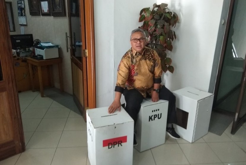 Ketua KPU, Arief Budiman, menduduki kotak suara untuk pemilu yang berbahan dasar karton kedap air, Senin (17/12). KPU menjelaskan latar belakang pemilihan bahan baku yang disebut kardus tersebut.