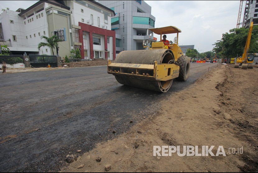 Pekerja memadatkan urukan tanah di lokasi jalan ambles di Jalan Raya Gubeng, Surabaya, Jawa Timur, Rabu (26/12/2018).