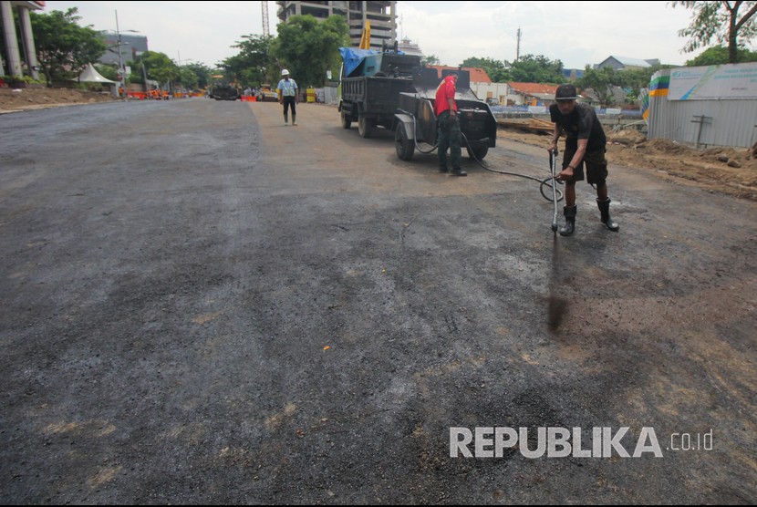 Pekerja melakukan proses 'prime coat' pada urukan tanah sebelum di aspal di lokasi jalan ambles di Jalan Raya Gubeng, Surabaya, Jawa Timur, Rabu (26/12/2018).