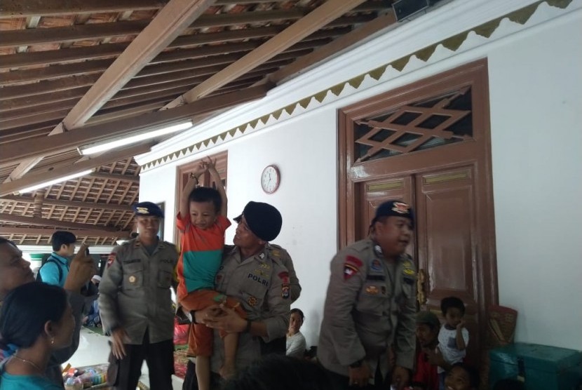 Personel Brimob Polda Banten melakukan pemulijan trauma kepada anak-anak pengungsi di Desa Pagedongan, Pandeglang, Banten. Kamis (27/12). 