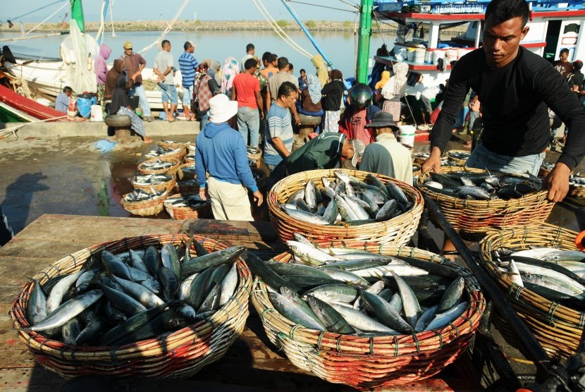 Nelayan memindahkan keranjang ikan hasil tangkapan.