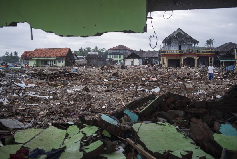 Warga berjalan di sisa-sisa bangunan yang rusak diterjang tsunami Selat Sunda di Sumur, Pandeglang, Banten, Kamis (3/1/2019). 