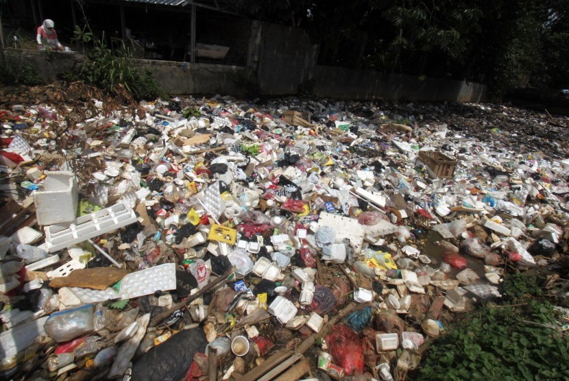 Seorang warga berdiri di bantaran sungai yang aliran airnya dipenuhi tumpukan sampah (Ilustrasi)