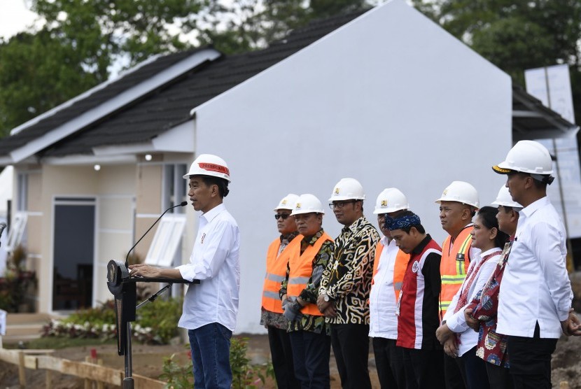 Presiden Joko Widodo (kiri) didampingi Ibu Negara Iriana Joko Widodo (ketiga kanan), Mensos Agus Gumiwang Kartasasmita (kanan), Menteri PUPR Basuki Hadimuljono (keenam kanan), Gubernur Jawa Barat Ridwan Kamil (keempat kiri) dan Dirut BTN Maryono (ketiga kiri) menyampaikan sambutan saat peletakan batu pertama perumahan Persatuan Pencukur Rambut Garut (PPRG) di Garut, Jawa Barat, Sabtu (19/1/2019). 