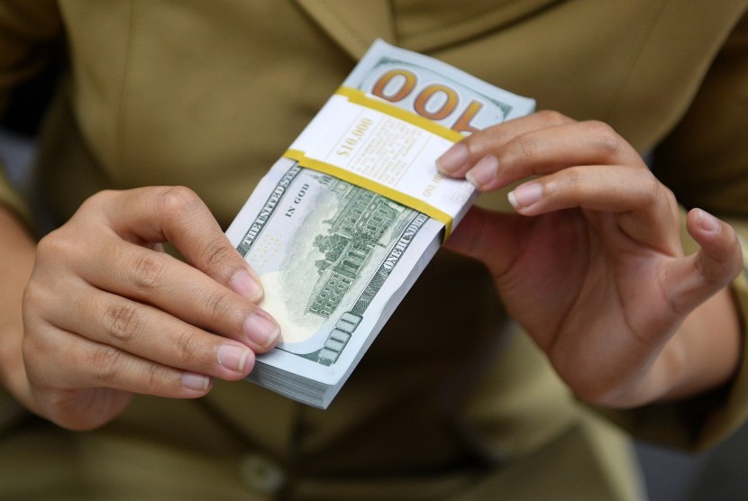 Karyawan menghitung mata uang dolar Amerika Serikat di gerai penukaran mata uang asing Ayu Masagung, Kwitang, Jakarta Pusat, Senin (28/1/2019).