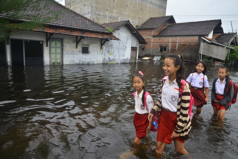 Sejumlah siswa melewati jalan yang terdampak banjir di Desa Gendok, Jati, Kudus, Jawa Tengah, Selasa (29/1/2019). 