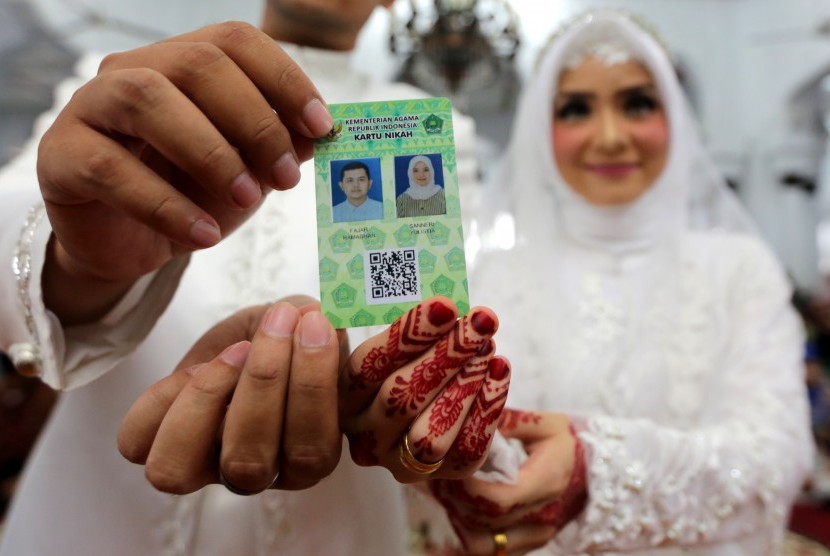 Pasangan pengantin memperlihatkan kartu nikah usai melaksanakan ijab kabul di Masjid Raya Baiturrahman, Banda Aceh, Aceh, Jumat (1/2/2019). 