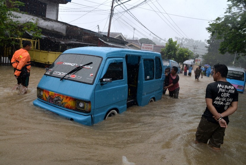 Warga mendorong angkot yang mogok akibat tergenang banjir di Kelurahan Mahawu, Manado, Sulawesi Utara, Jumat (1/2/2019).