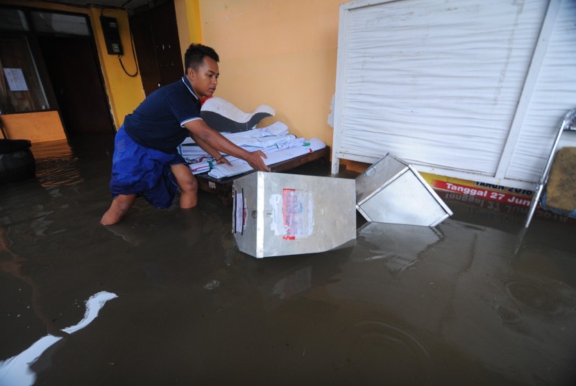Warga mengangkat kotak suara yang terendam banjir di Kantor KPU Pamekasan.