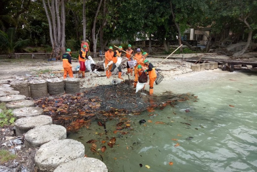 Petugas Suku Dinas LH Kepulauan Seribu membersihkan limbah minyak yang mengkristal di Pulau Pantara, Senin (4/2) lalu.