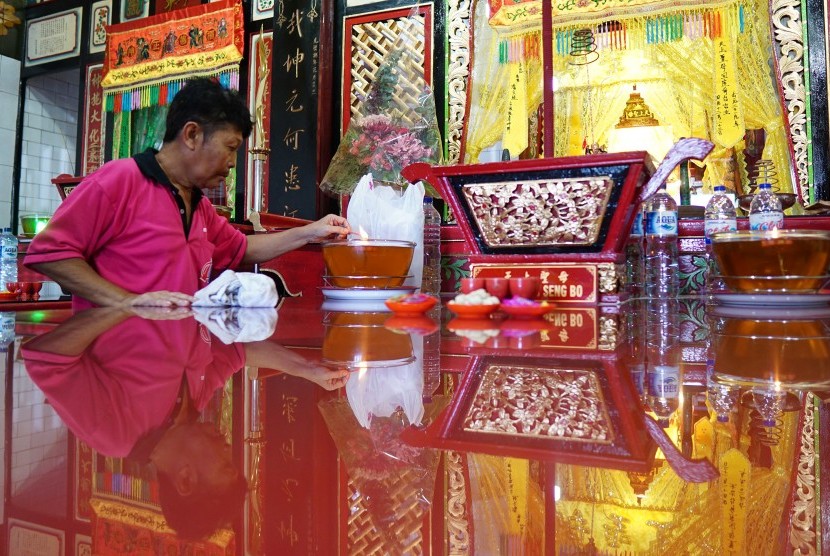 Petugas menyalakan lilin dan membersihkan perlengkapan doa di sebuah klenteng (ilustrasi)