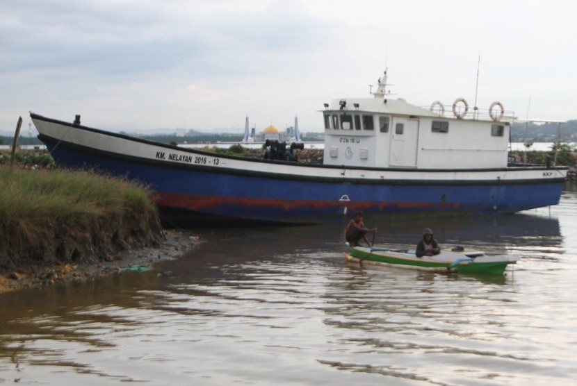 Dua nelayan mendayung sampannya di dekat KM Nelayan 2016 - 13 bantuan dari Kementerian Kelautan dan Perikanan yang rusak di Teluk Kendari, Kendari, Sulawesi Tenggara, Senin (4/2/2019).