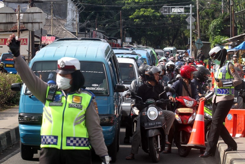 Polisi mengatur lalu lintas untuk mengurai antrean kendaraan menuju kawasan Puncak, Gadog, Bogor, Jawa Barat, Selasa (5/2/2019).
