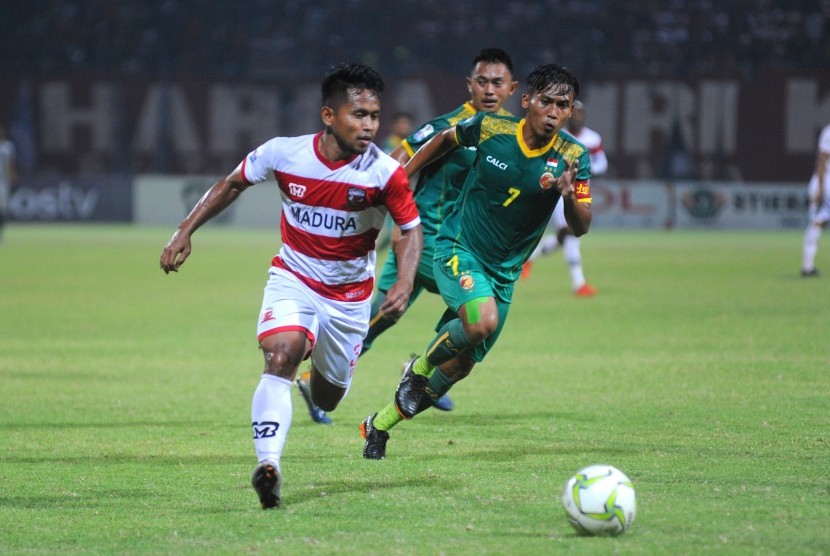 Pesepak bola Madura United (MU) Andik Vermansyah (kiri) melewati pesepak bola Sriwijaya FC Hafit Ibrahim (kanan) dalam Laga 16 Besar Leg pertama Piala Indonesia di Stadion Gelora Pamelingan (SGRP) Pamekasan, Jawa Timur, Ahad (17/2/2019).