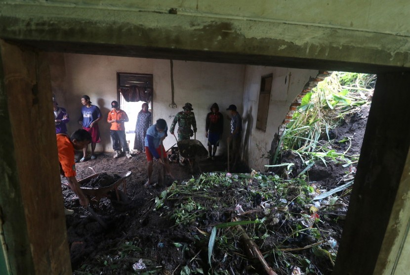 Warga bergotong royong membersihkan rumah yang terkena tanah longsor di Desa Pamongan, Kediri, Jawa Timur, Rabu (20/2/2019).