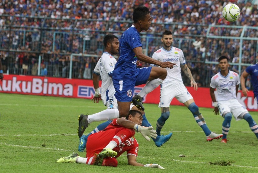 Arema Gagal Lolos: Pesepak bola Arema FC, Ridwan Tawainela (kiri) berebut bola dengan penjaga gawang Persib Bandung, M Natsir (bawah) dalam pertandingan babak 16 Besar Leg Kedua Piala Indonesia di Stadion Kanjuruhan, Malang, Jawa Timur, Jumat (22/2/2019).