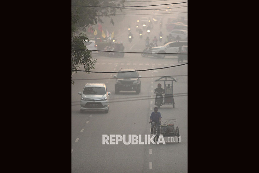 Warga melintas di jalan yang berkabut asap pekat dari kebakaran hutan dan lahan (karhutla) di kota Dumai, Riau. (ilustrasi)