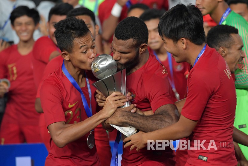 Pemain Timnas U-22 Sani Riski Fauzi (kiri) bersama Marinus Wanewar (tengah) mencium Piala AFF U-22 seusai penganugerahan piala di Stadion Nasional Olimpiade Phnom Penh, Kamboja, Selasa (26/2/2019).