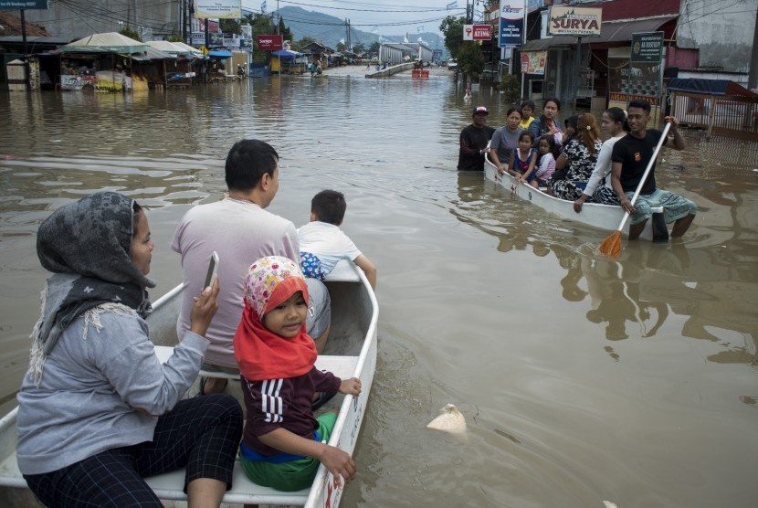 Warga menggunakan perahu melintasi banjir di Jalan Raya Dayeuhkolot, Kabupaten Bandung, Jawa Barat, Kamis (7/3/2019).