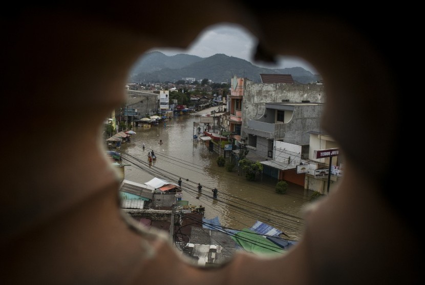 Warga melintasi banjir di Jalan Raya Dayeuhkolot, Kabupaten Bandung, Jawa Barat, Kamis (7/3/2019).