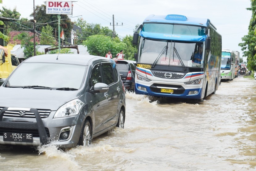 Sejumlah kendaraan bermotor menerobos banjir yang merendam jalan raya jalur utama Surabaya - Yogyakarta di Desa Garon, Balerejo, Kabupaten Madiun, Jawa Timur, Kamis (7/3/2019).