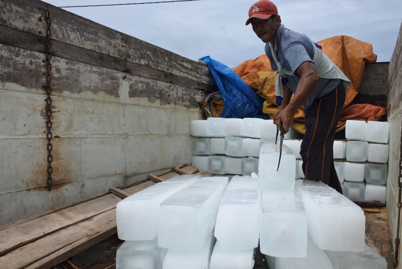 Pekerja menurunkan 'es balok' ke perahu nelayan di perairan Plawangan Puger, Jember, Jawa Timur, Jumat (8/3/2019).