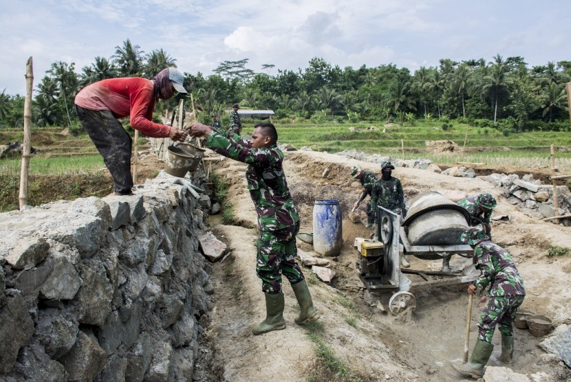 Sejumlah anggota TNI dan warga bergotong royong membangun jembatan antar Desa saat program Tentara Manunggal Membangun Desa (TMMD) di Desa Purwasedar, Ciracap, Kabupaten Sukabumi, Jawa Barat, Jumat (8/3/2019).