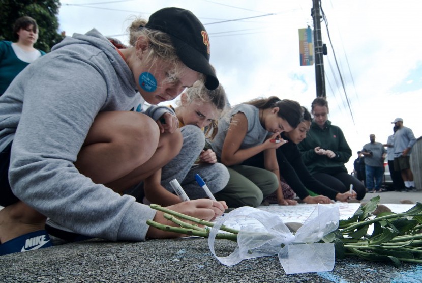 Warga menulis pesan di dekat bunga yang diletakkan di depan Masjid Wellington, Kilbirnie, Wellington, Selandia Baru, Sabtu (16/3/2019).