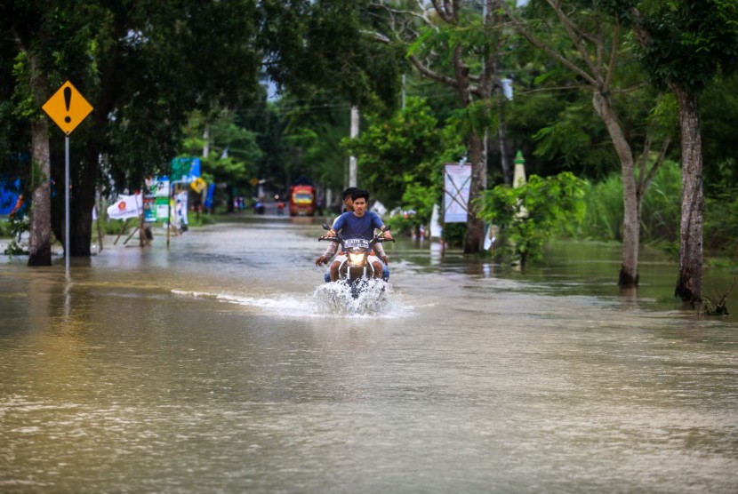 Warga melintasi jalan yang tergenang banjir di kawasan Panjatan, Kulon Progo, DI Yogyakarata, Senin (18/03/2019).