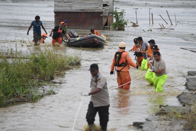 Tim SAR Gabungan mendorong perahu karet yang memuat jenazah korban banjir bandang Sentani yang di temukan di sekitar perumahan Gajah Mada di Sentani, Jaya Pura, Papua, Selasa (19/3/2019).
