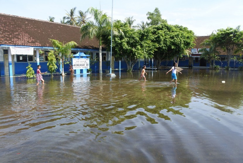 Siswa melintasi banjir di halaman SDN Wonoasri 01, Tempurejo, Jember (ilustrasi-