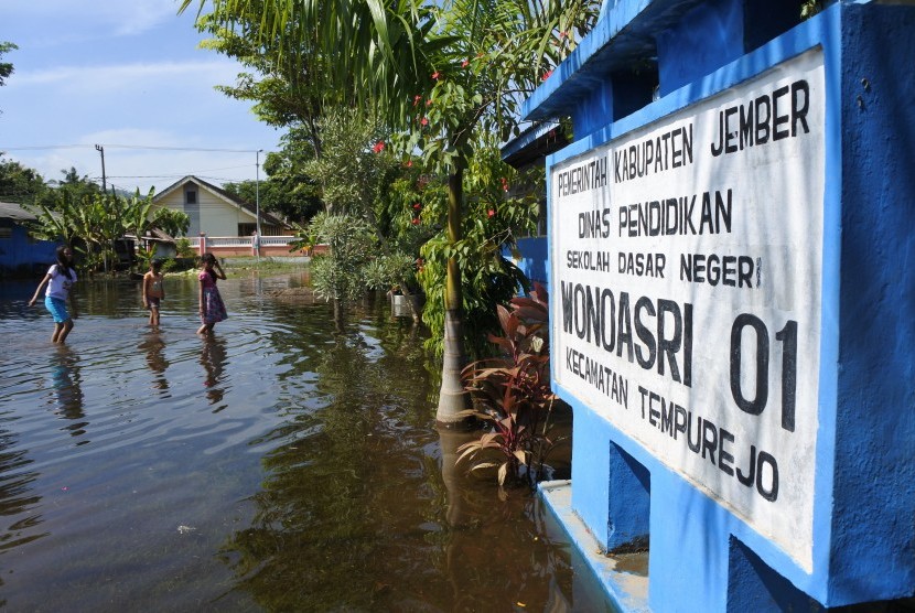 Siswa melintasi banjir di halaman SDN Wonoasri 01, Tempurejo, Jember, Jawa Timur, Rabu (20/3/2019).