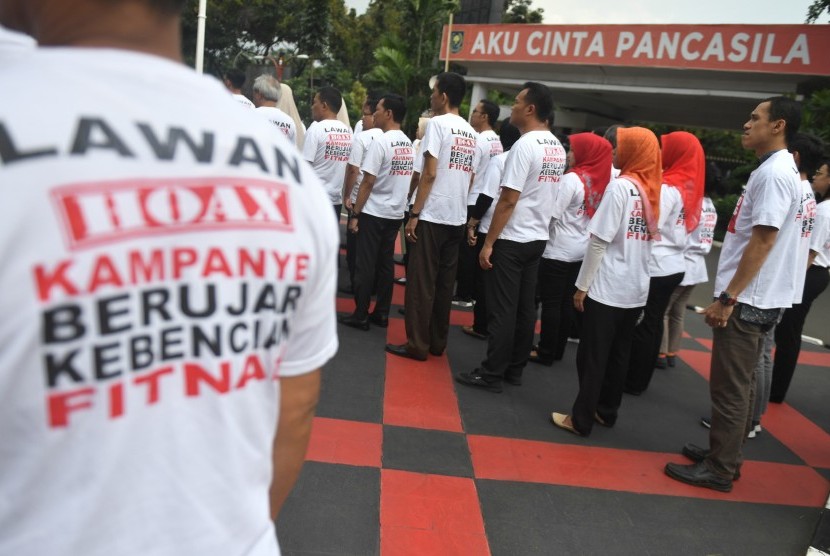Sejumlah aparatur sipil negara (ASN) mengenakan kaus bertuliskan ajakan untuk melawan hoaks saat apel di Kemendagri, Jakarta, Jumat (22/3).