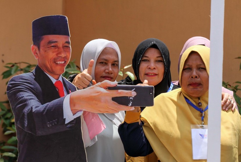 Sejumlah kaum perempuan pendukung calon Presiden nomor urut 01 Joko Widodo – Ma’ruf Amin berfoto dengan spot photo Jokowi usai kampanye terbuka Jokowi di Lhokseumawe, Aceh, Selasa (26/3/2019).