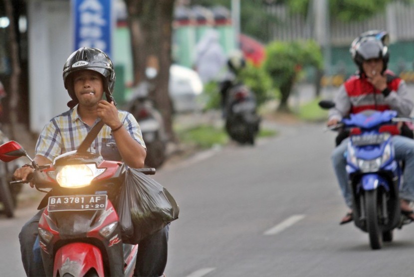 Sejumlah pengendara merokok sambil mengendarai sepeda motor, di Padang, Sumatera Barat, Jumat (29/3/2019). 