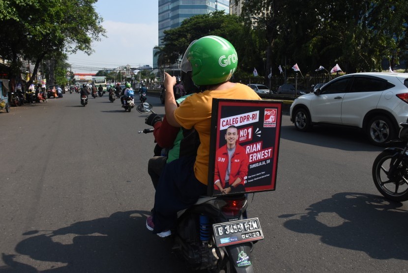 Sebuah poster salah satu caleg terpampang pada kendaraan ojek daring saat melintas di kawasan Senen, Jakarta, Kamis (4/4/2019).