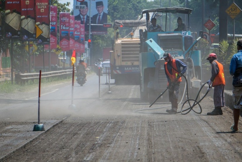 Pekerja memperbaiki jalan rusak di jalur pantura Batang, Jawa Tengah.